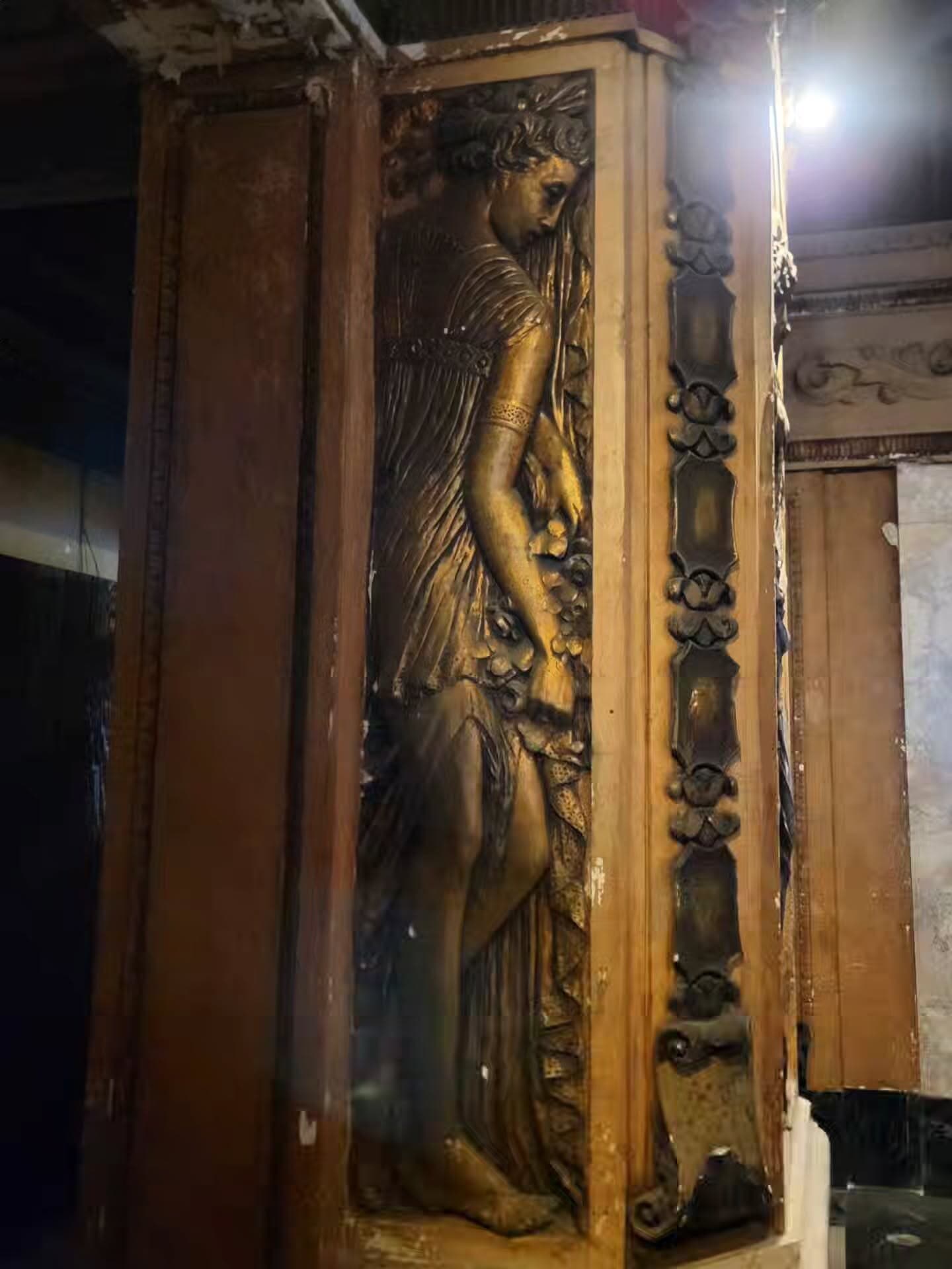 A gilded relief sculpture of a robed woman on an ornate pier inside the Uptown Theatre.